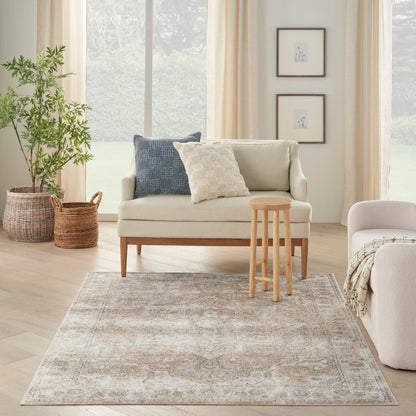Neutral living room with beige sofa, navy and cream pillows, light wood stool, muted-pattern rug, and wicker plant baskets.
