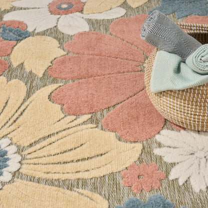 Round wicker basket with folded blue and mint towels atop a large colorful floral rug.