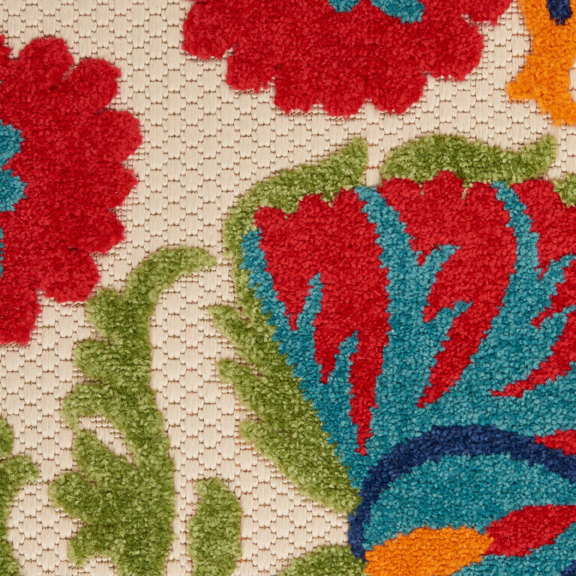 Close-up of a beige floral rug with bold red, blue, green and orange petals and textured pile.