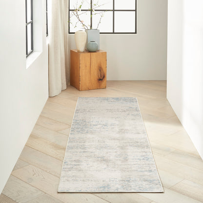 Minimalist hallway with pale wood flooring, a light grey-blue runner rug, and a wooden pedestal with ceramic vases.
