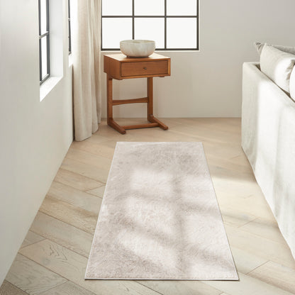 Light beige runner rug on pale wood floor beside sofa; wooden side table with ceramic bowl near window.