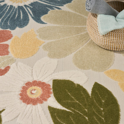 Floral patterned rug with cream/green/yellow hues and large petals, beside a woven basket with blue and mint ribbons.