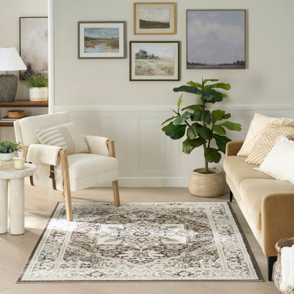 Neutral living room with beige sofa, cream armchair, beige-brown rug, fiddle-leaf fig in woven basket, framed landscape art.