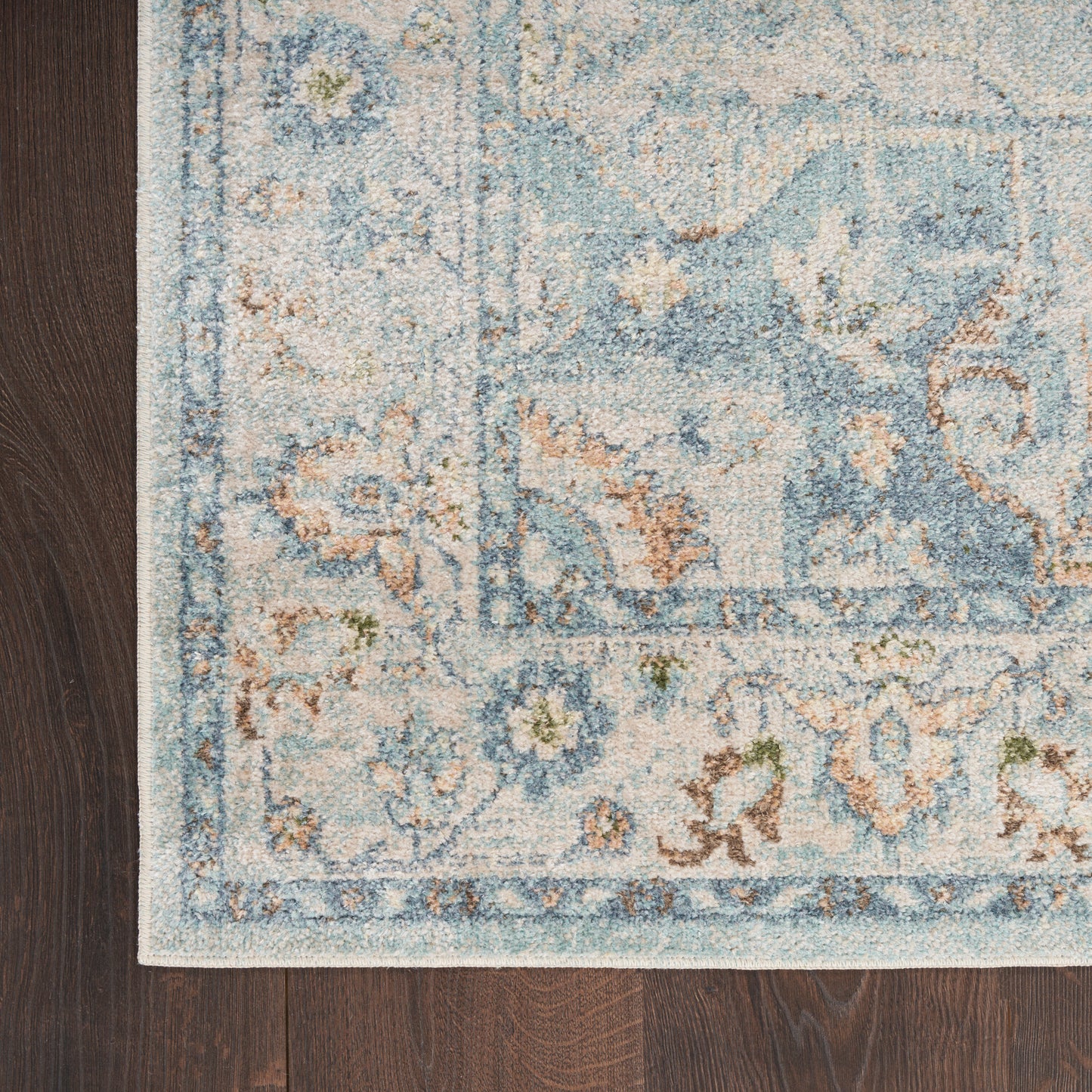 Ornate blue and cream runner rug with floral motifs on dark wood floor.