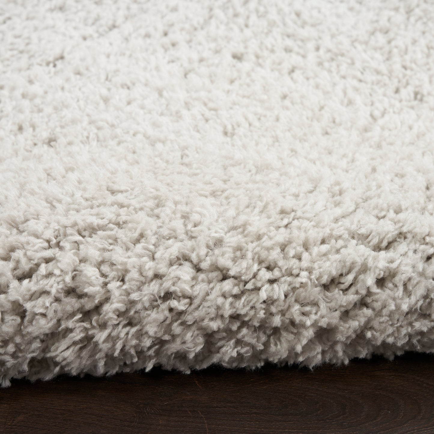 Cream shag rug with plush, fluffy pile on dark wood floor.