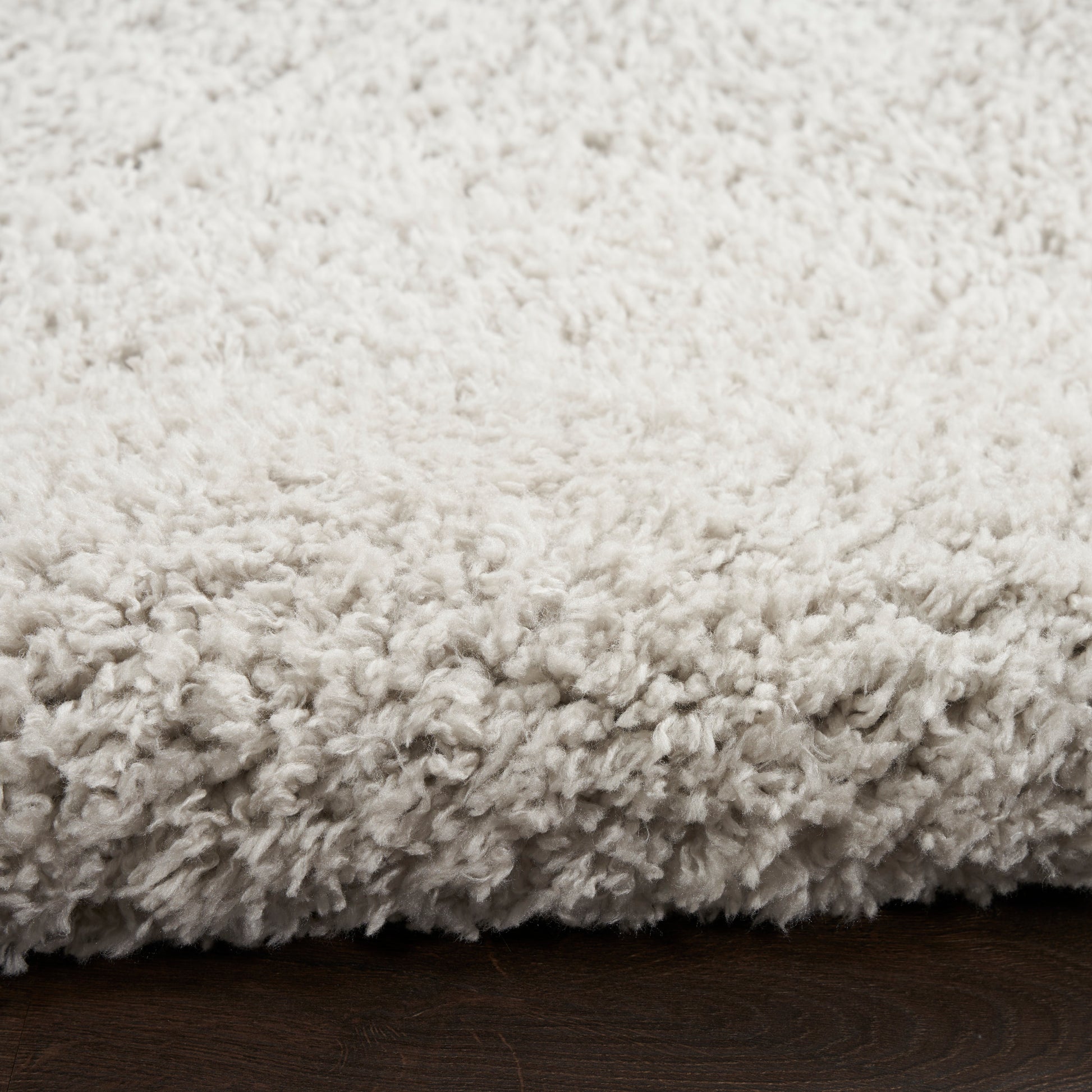 Cream shag rug with plush, fluffy pile on dark wood floor.
