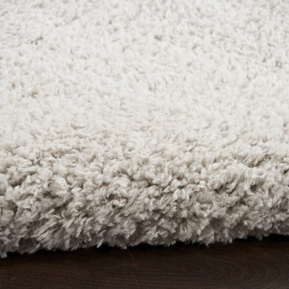 Cream shag rug with plush, fluffy pile on dark wood floor.
