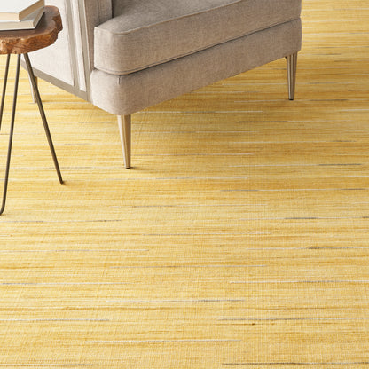 Beige upholstered sofa with tapered metal legs on a yellow striped rug; a wooden top side table with black metal legs nearby.