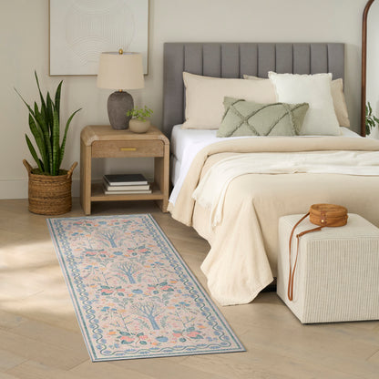 Neutral bedroom with gray tufted headboard, beige bedding, pastel rug runner, snake plant in wicker basket, and cream ottoman