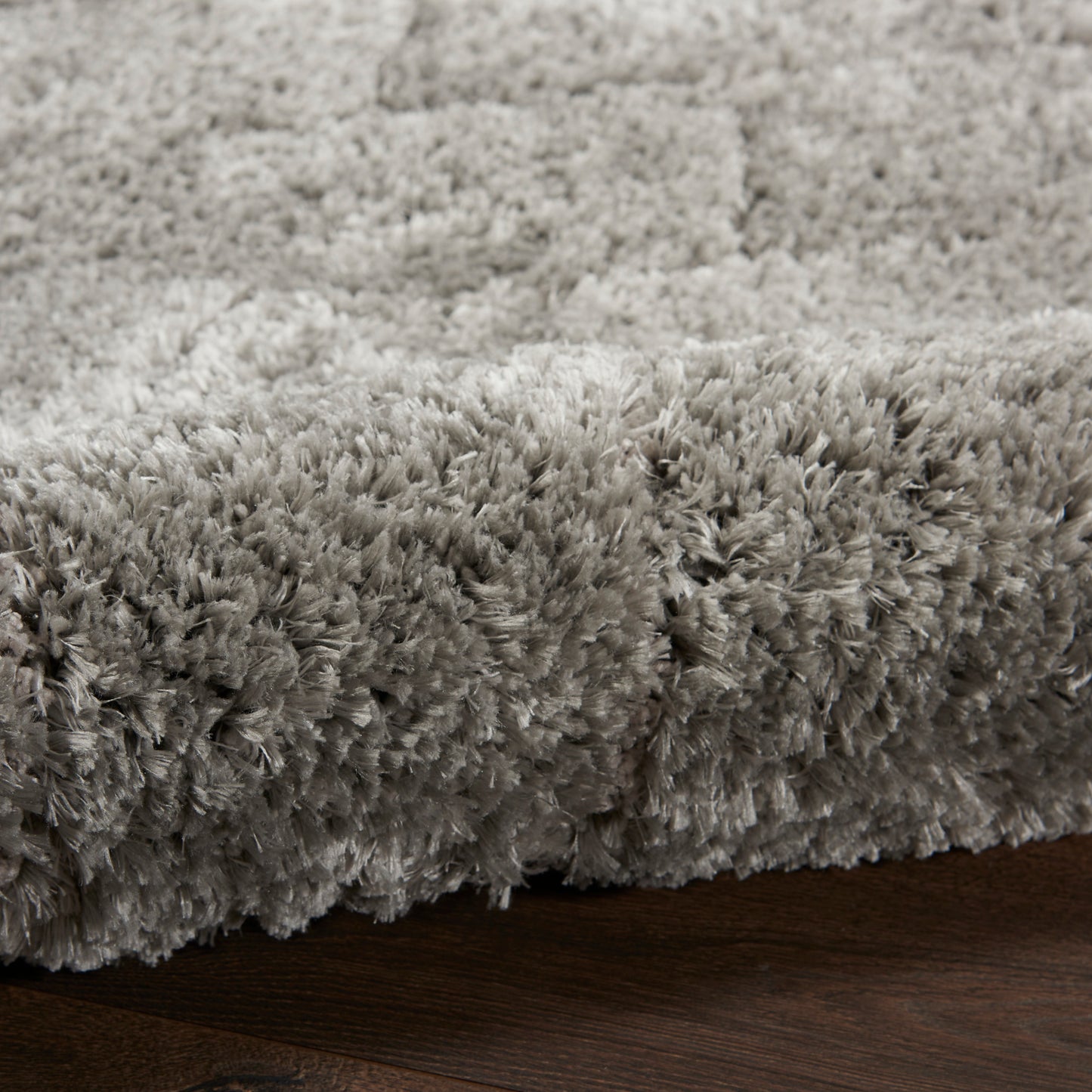 Soft gray high-pile shag rug with plush fibers on dark wood floor.