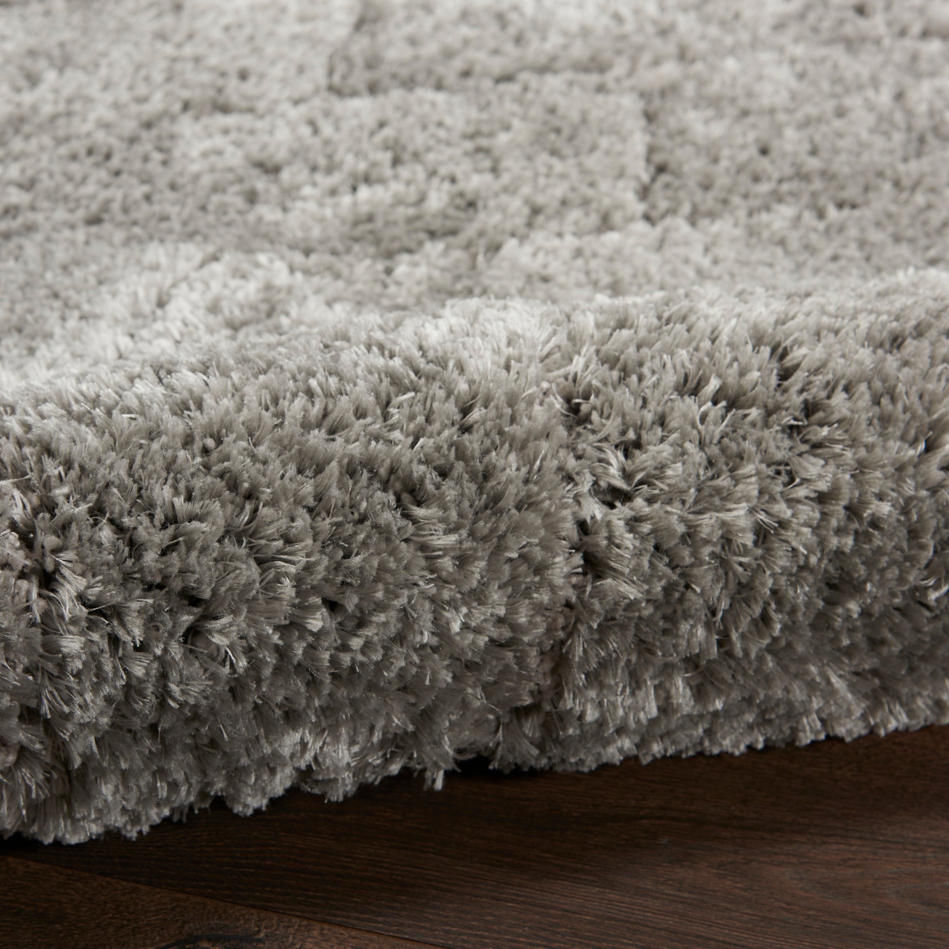 Soft gray high-pile shag rug with plush fibers on dark wood floor.