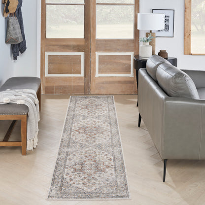 Persian-inspired runner rug in muted ivory, beige and grey with a bordered floral medallion in a living room hallway.
