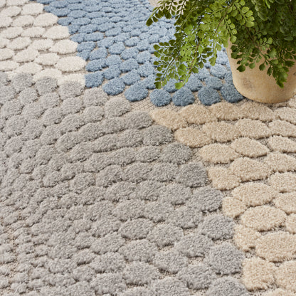 Bubble tufted area rug in gray, beige & light blue with a green potted plant nearby.
