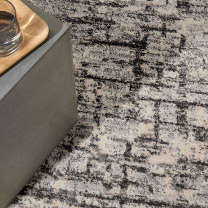 Grey concrete side table with a light wood tray & glass on a black-and-white patterned rug.