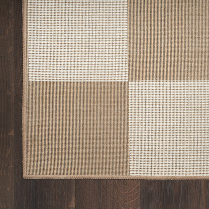 Beige, ivory and tan patchwork rug with woven square textures on dark wood floor.