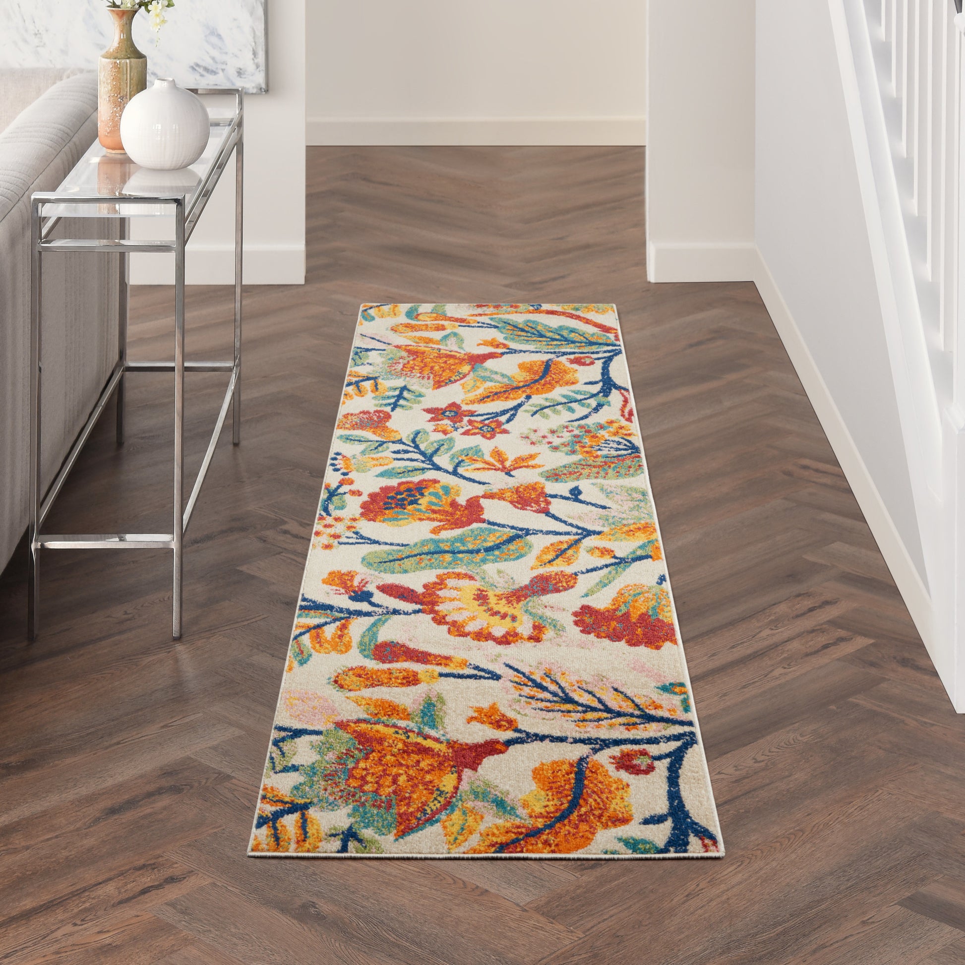 Colorful hallway runner with orange, blue & yellow floral birds on light background; wood chevron floor.