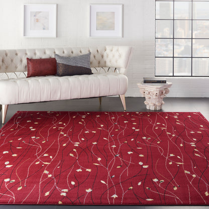 Cream tufted sofa with red and dark cushions on a red area rug with white vine patterns.
