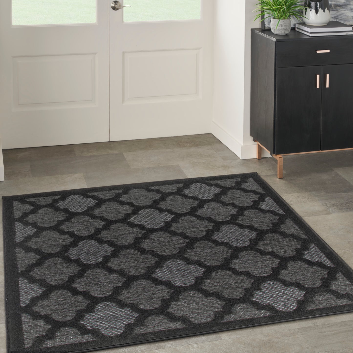 Square black and gray entryway rug with a woven quatrefoil lattice pattern.