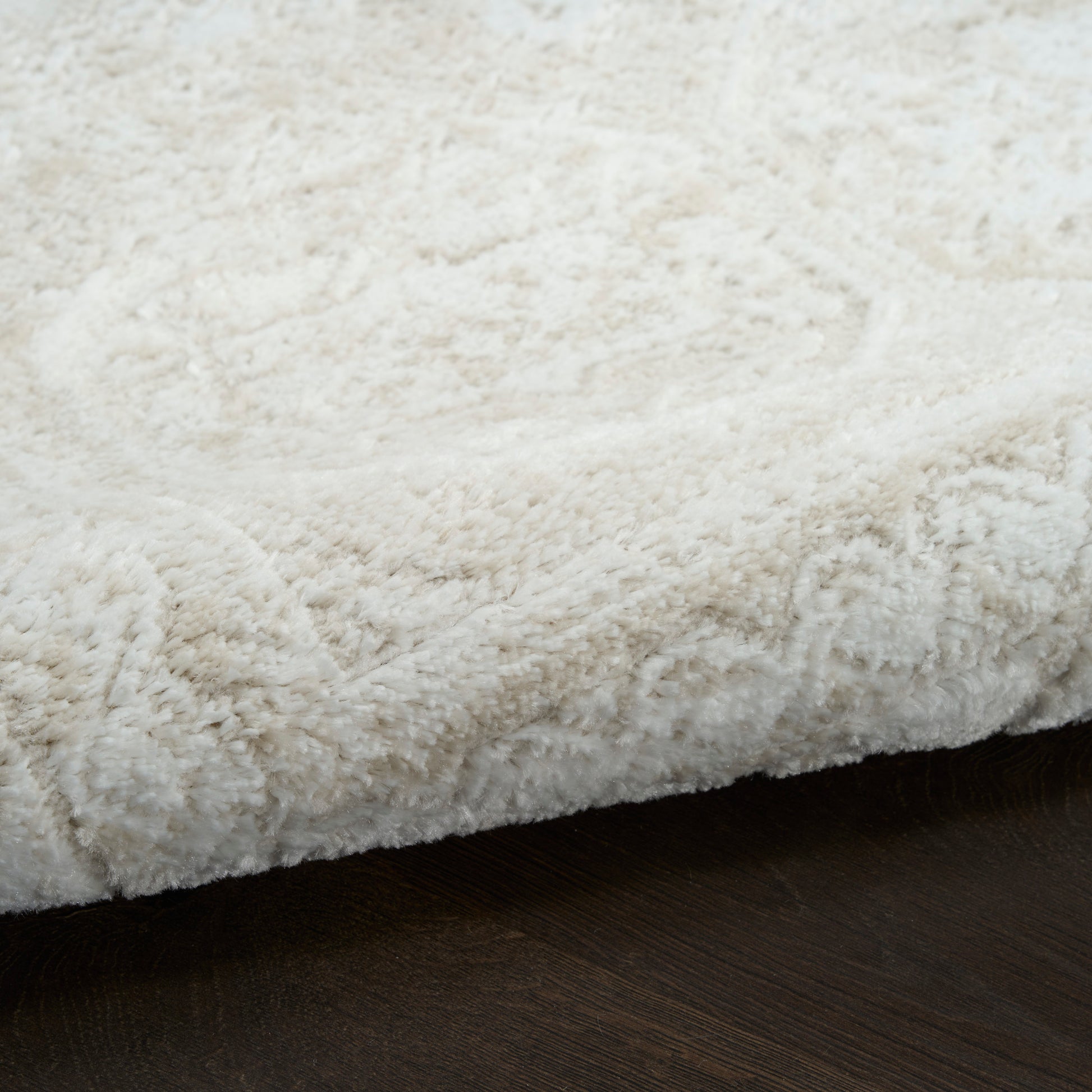 Cream plush shag rug with thick fluffy pile on dark wooden floor.