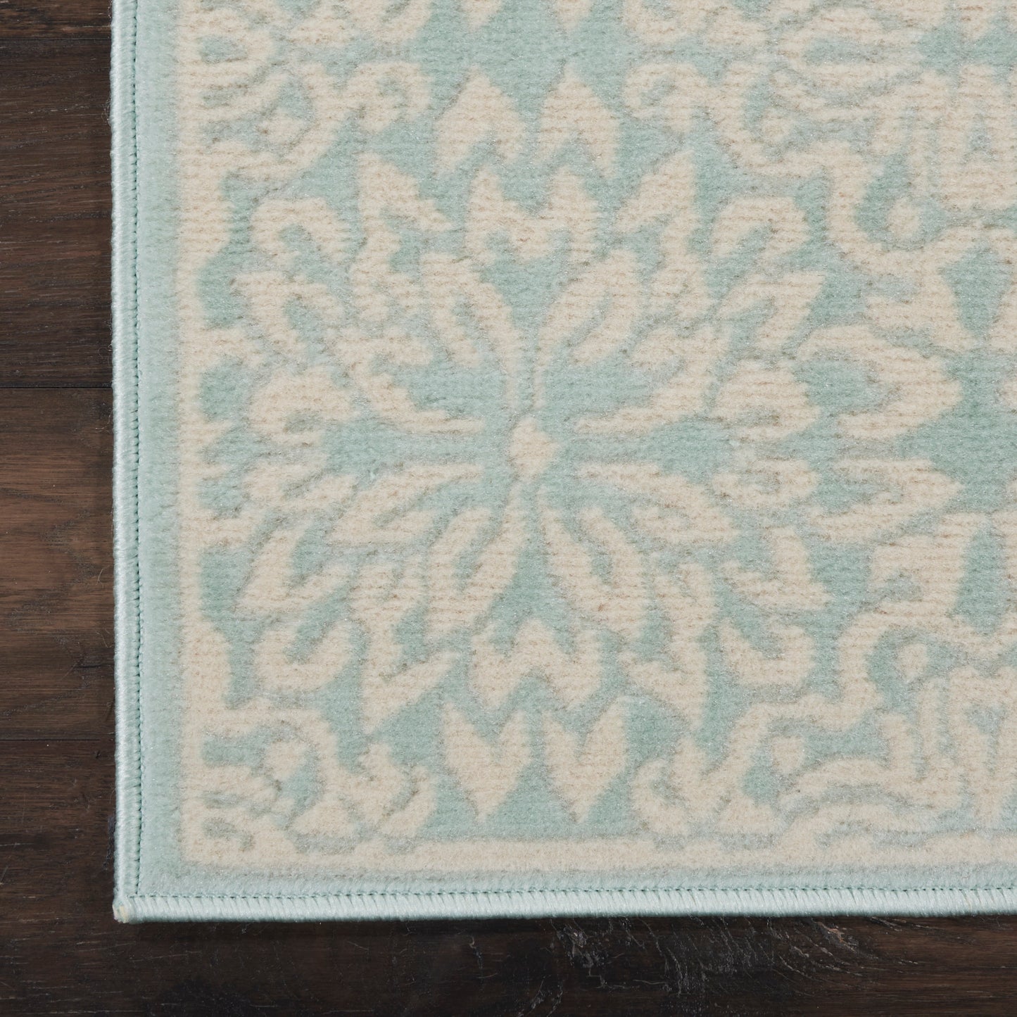 Light blue & ivory floral patterned hallway runner with a stitched blue border on a wooden floor.