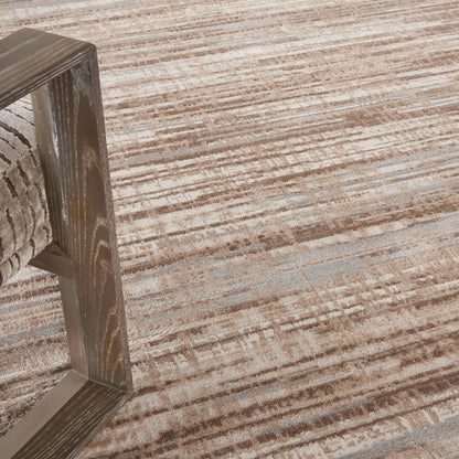 Dark stained wooden furniture leg with fabric upholstery on a beige-brown striped rug.