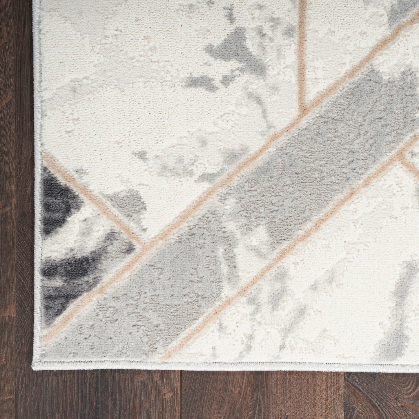 Cream area rug with gray marbled pattern and a bold diagonal gray stripe bordered in beige, on dark wood floor.