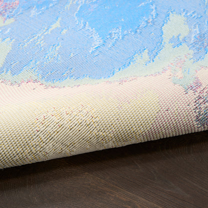 Pastel-toned woven rug with blue, cream and pink patterns, partially rolled on dark wood floor.