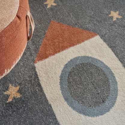 Tufted kids' area rug with a retro rocket motif: navy background, beige rocket with orange tip and blue window, yellow stars.