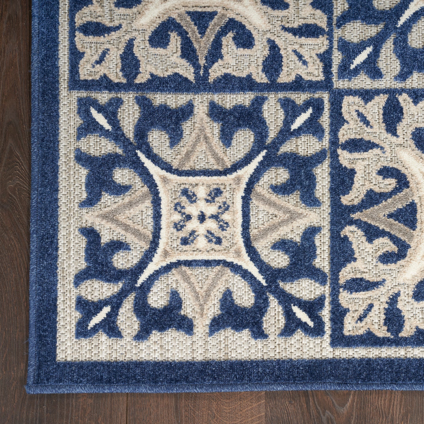 Navy blue & cream damask patterned area rug with a thick navy border on a wood floor.