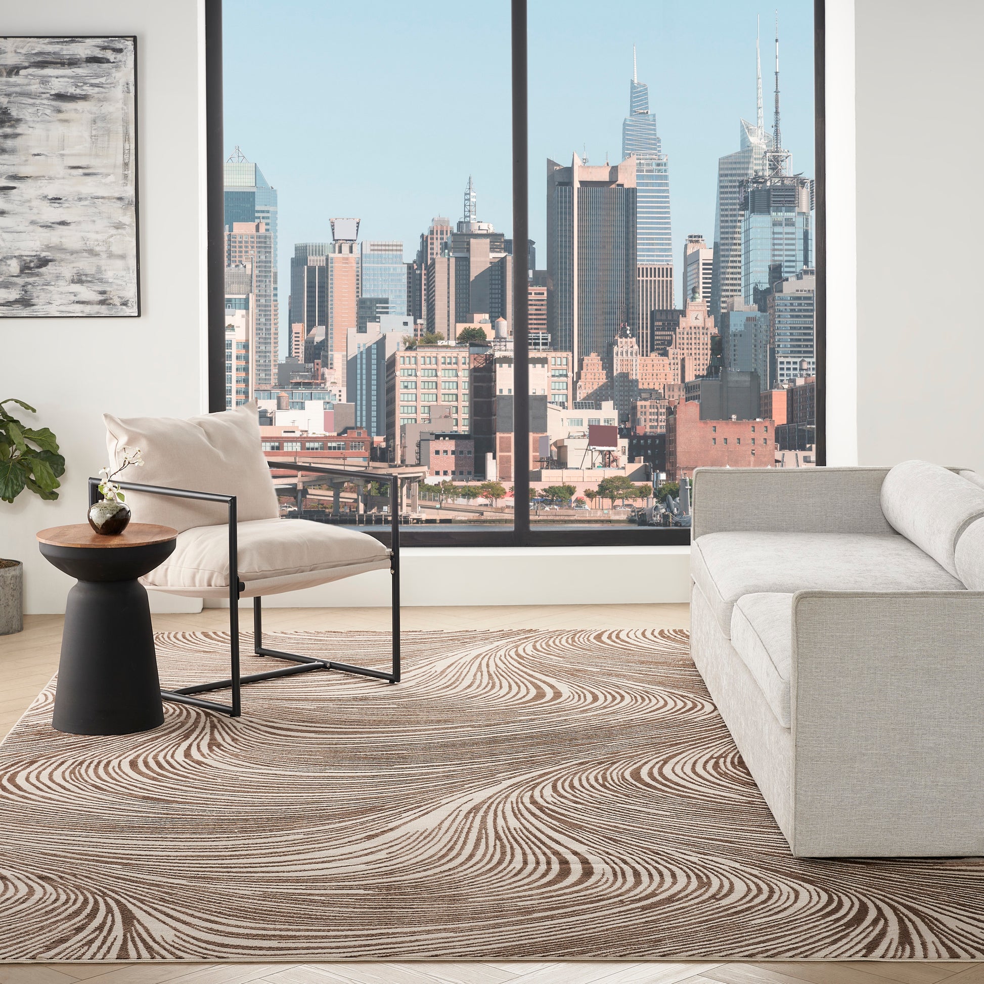 Modern living room with a city skyline window, beige metal-frame armchair, gray sofa, black wood-top side table, swirl rug.