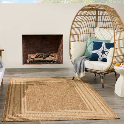 Outdoor patio with a woven rattan egg chair and neutral cushions on a natural jute rug beside a brick fireplace.