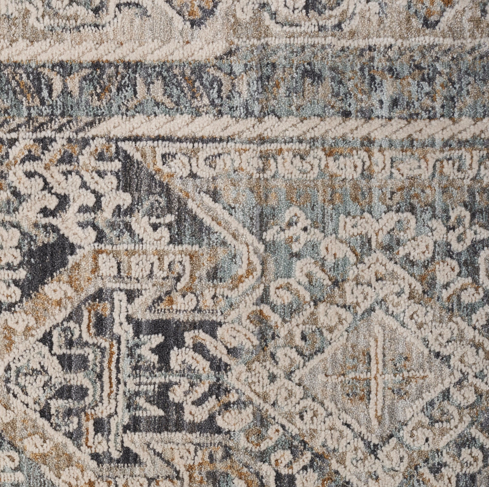 Close-up of a blue-gray and beige patterned rug with geometric and floral motifs in a distressed vintage style.