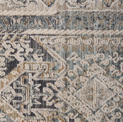 Close-up of a blue-gray and beige patterned rug with geometric and floral motifs in a distressed vintage style.