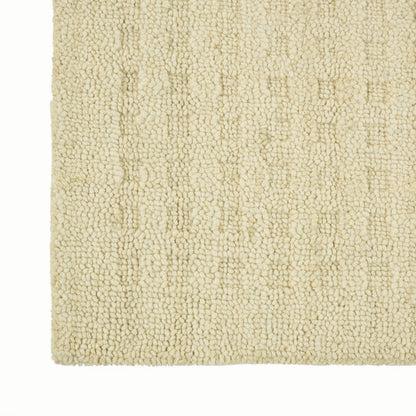 Beige plush shag rug corner with dense boucle texture and soft, cozy fibers.