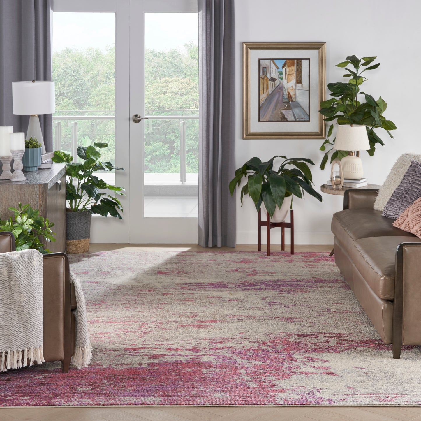 Cozy living room with brown leather sofa, green potted plants, framed art, and pink-beige patterned rug.