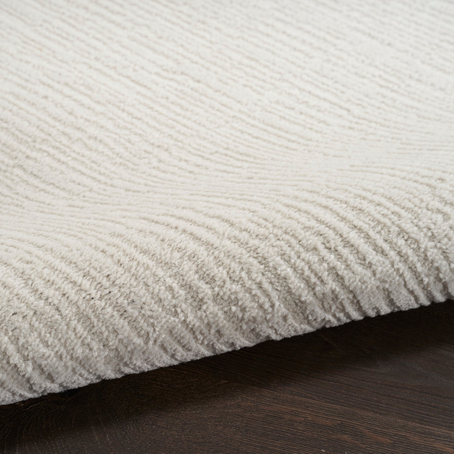 Cream tufted rug with ribbed, corduroy-like pile resting on dark wood floor