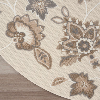 Round beige rug with cream and taupe floral pattern; woven textured surface and curved edge.