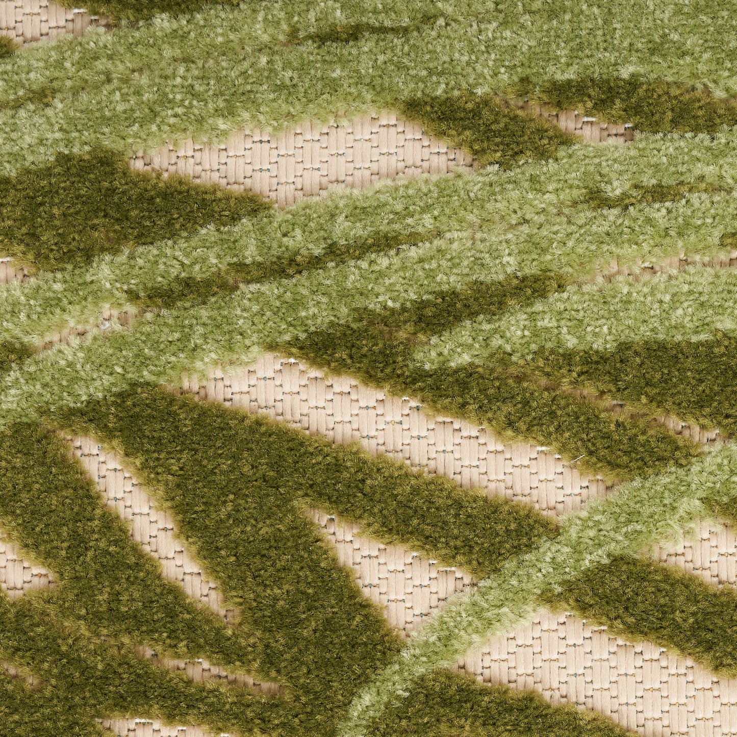 Outdoor shag rug with moss and olive green zigzag stripes on a beige woven base.
