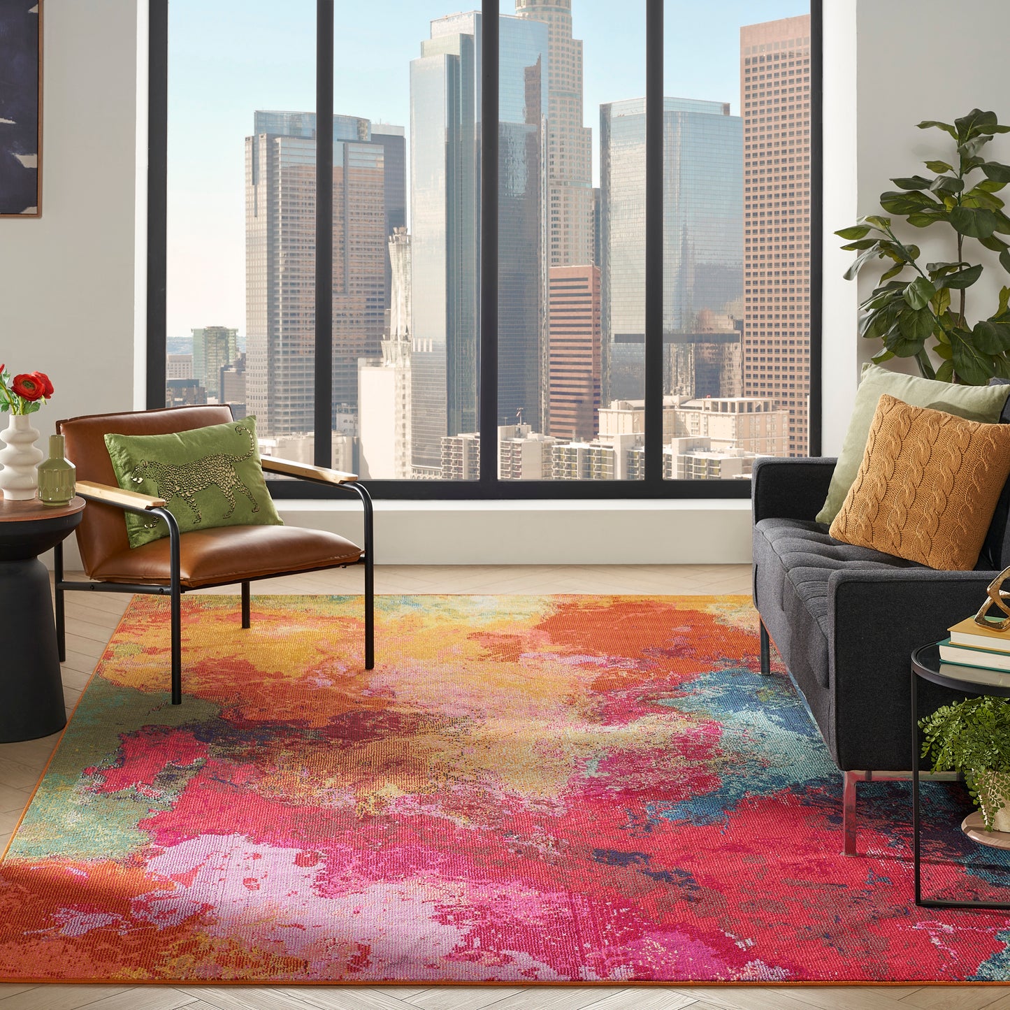 Bright urban living room with vibrant abstract rug, leather lounge chair, dark sofa, colorful pillows, and city skyline view.