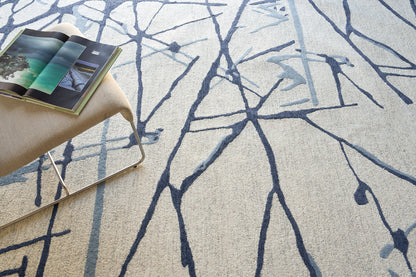 Beige textured rug with dark blue abstract branch pattern.