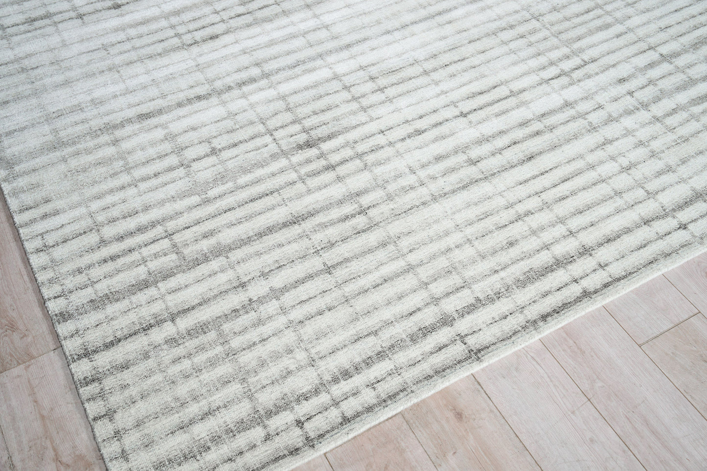 Light gray & ivory striped area rug with a soft, textured pile on light wood flooring.