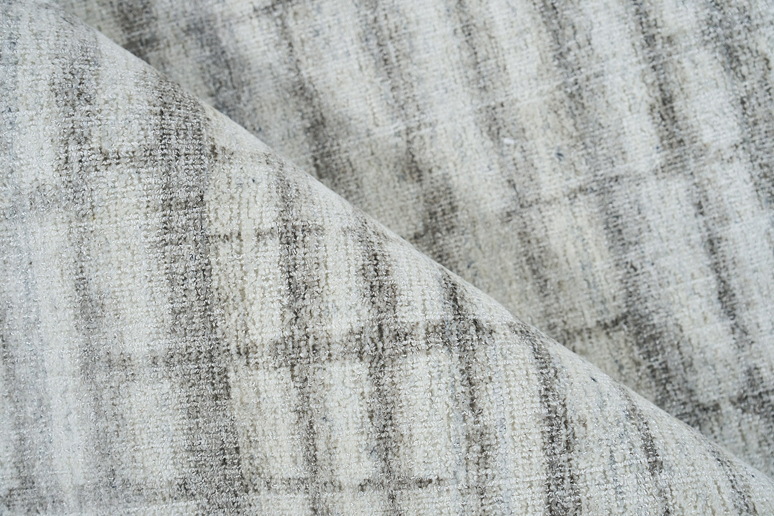 Soft grey plaid rug with a brushed, textured weave; draped fold suggests a cozy, hand-loomed look.