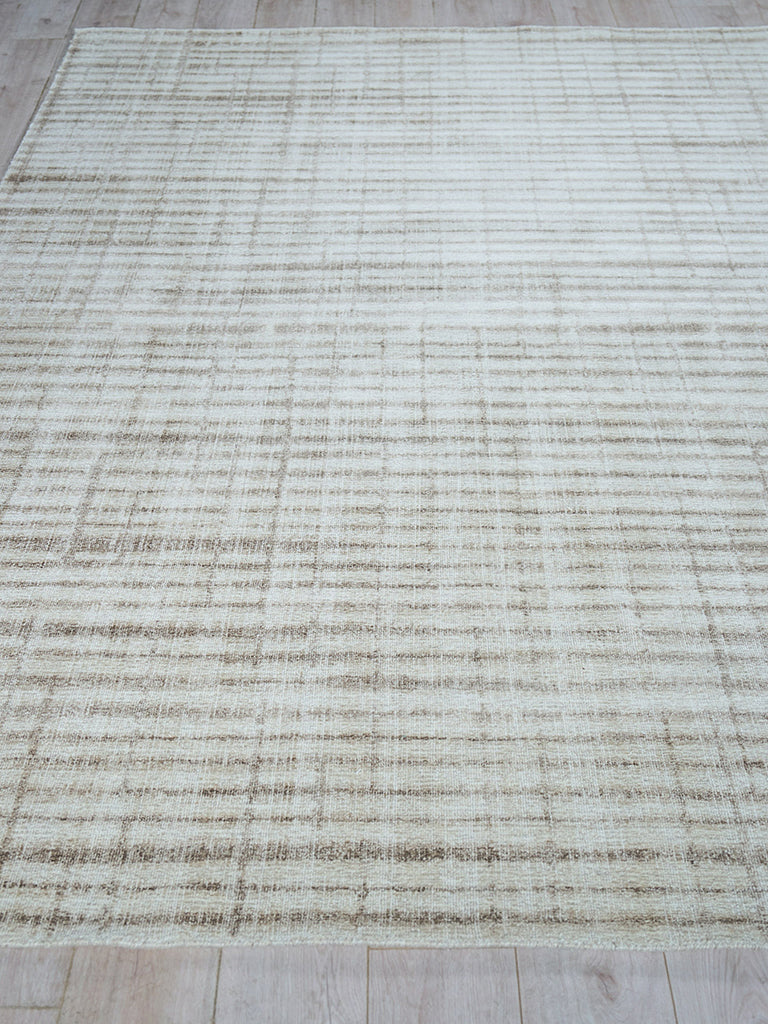 Beige hand-loomed rug with a subtle taupe grid pattern on a cream background; modern distressed look.