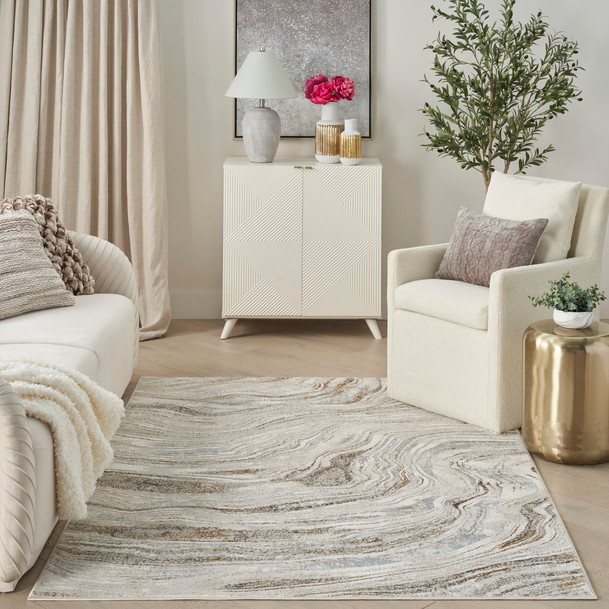 Neutral living room with cream cabinet featuring diagonal paneling, beige sofa, marbled rug, and gold side table