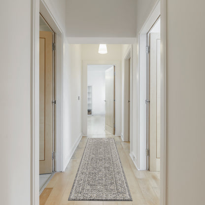 Bright white hallway with light wood doors, beige walls, and a long gray patterned runner rug under soft overhead light.