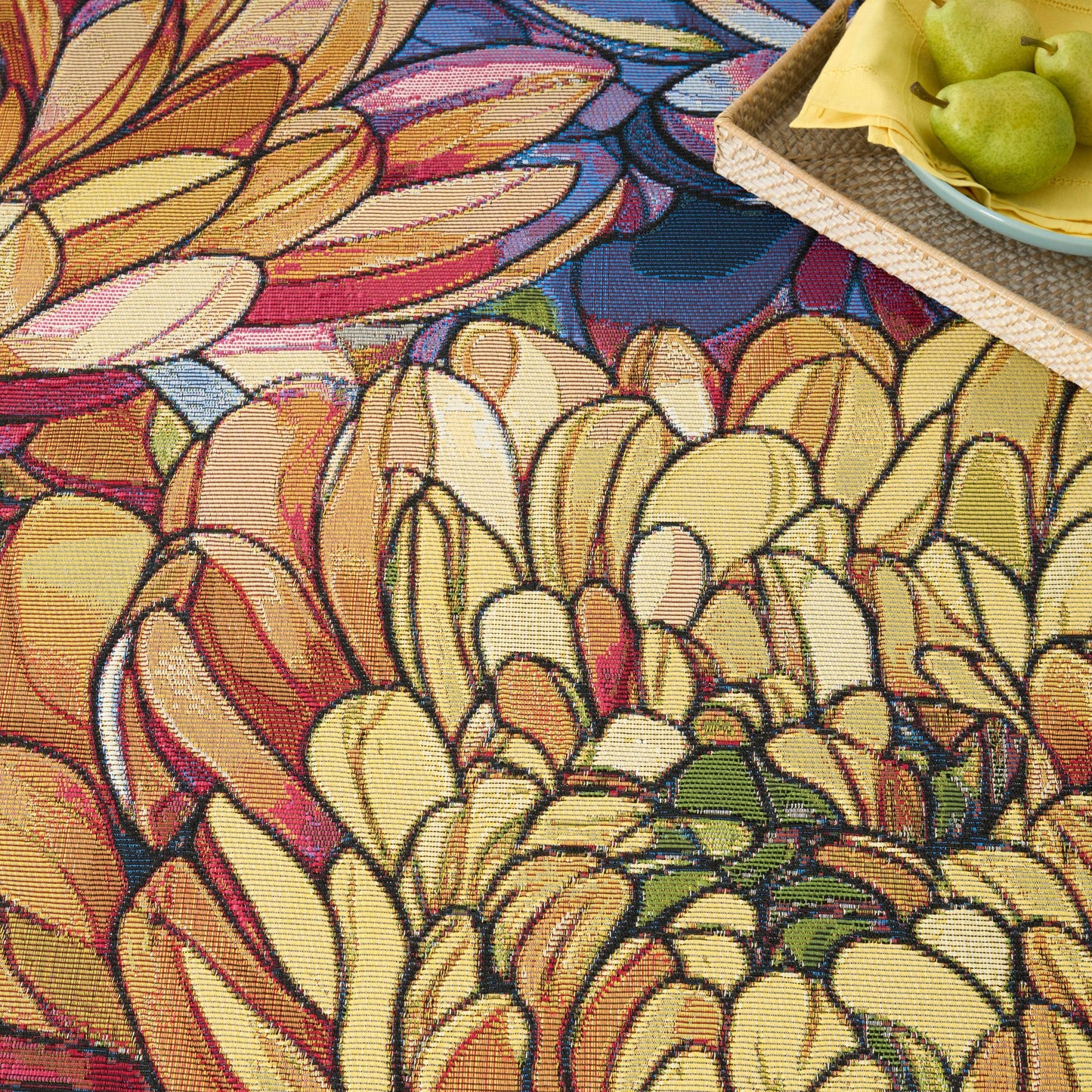 Vibrant multicolor floral-pattern rug with yellow, orange and pink petals; woven texture, top-right tray of pears.