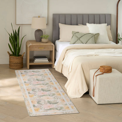 Neutral bedroom with gray tufted headboard, beige bedding, pastel floral rug runner, wooden nightstand, potted plant.
