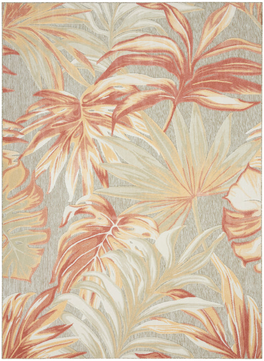 Tropical palm leaf rug in peach, cream and beige tones on a gray textured background.