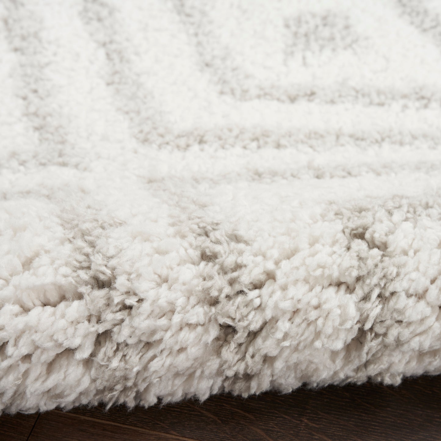 Ivory shag rug with ultra-soft, thick plush pile and visible edge on dark wood floor.