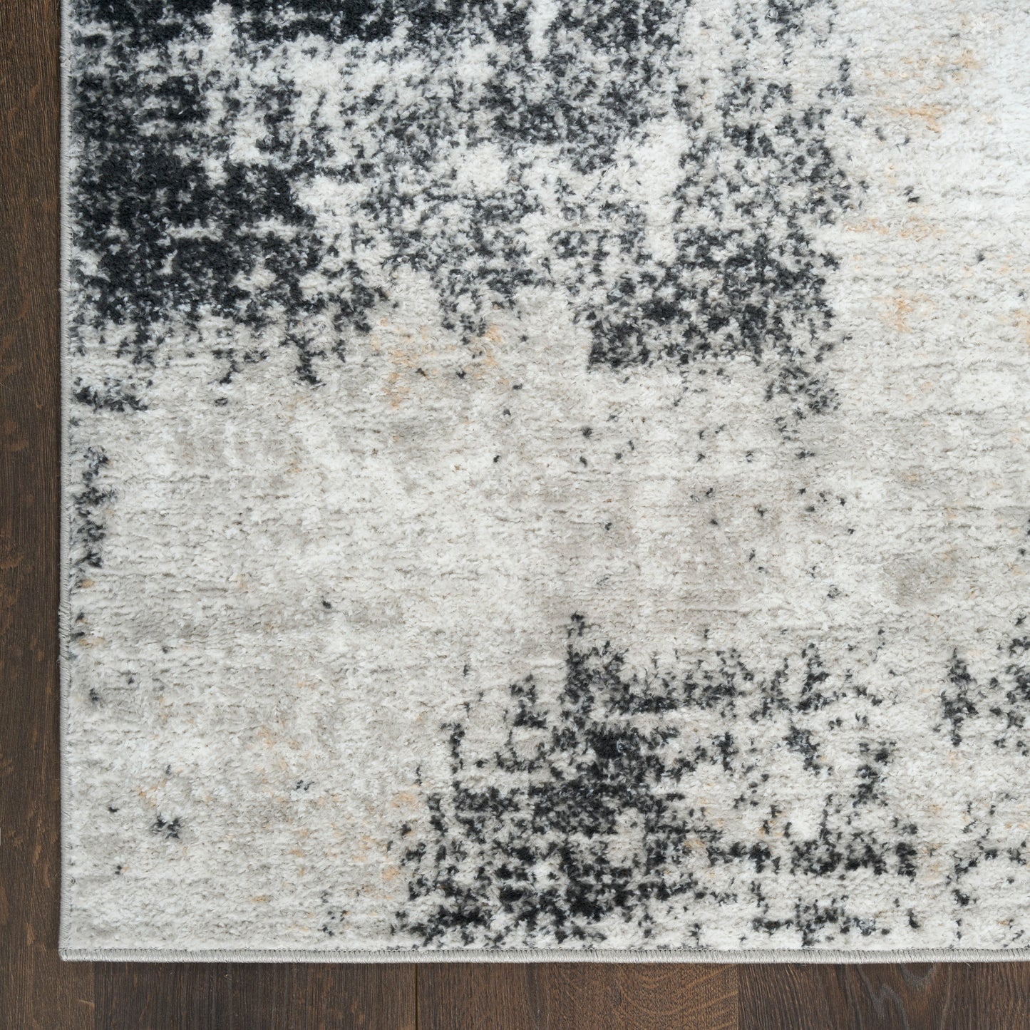Rectangular soft-pile rug in ivory and cream with charcoal and navy abstract blotches; modern distressed living-room style.